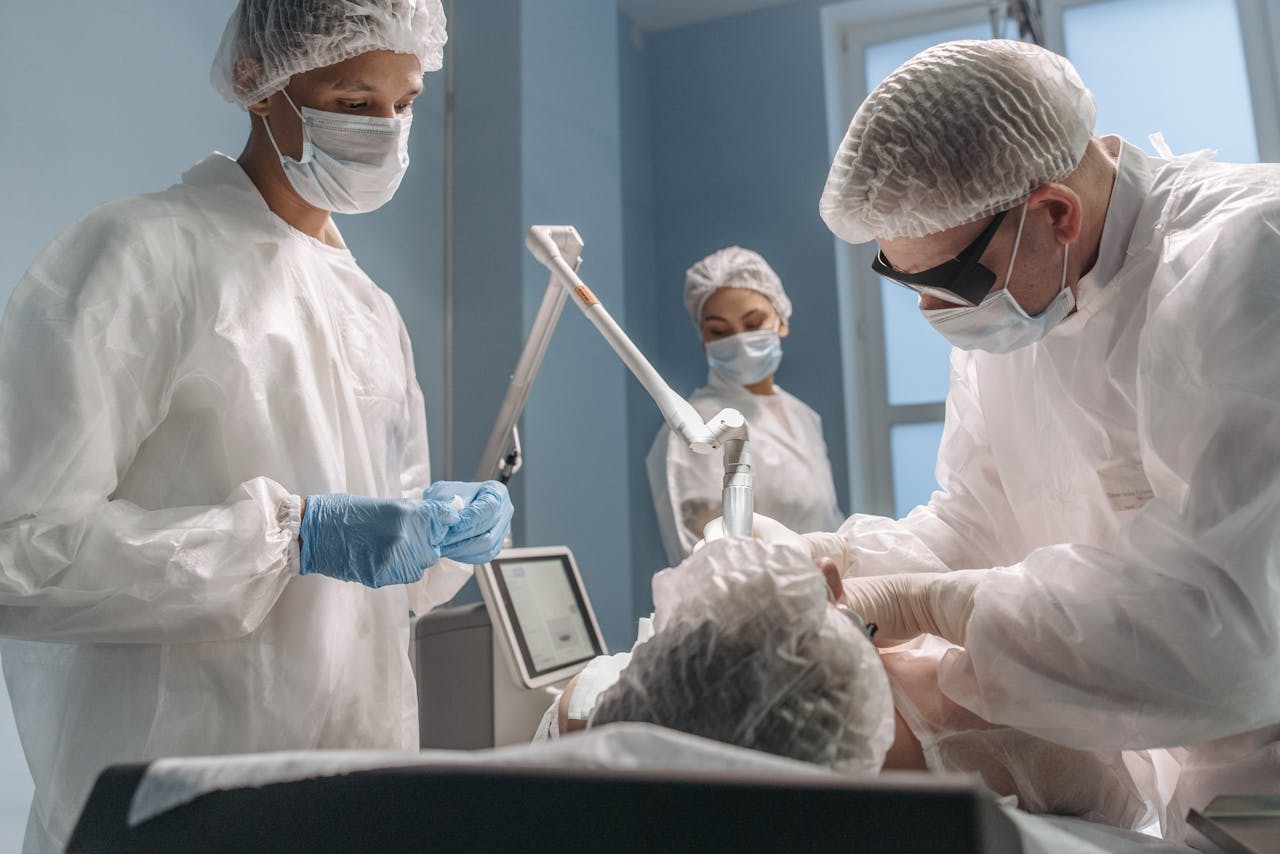 Healthcare professionals in an operating room performing a procedure wearing protective gear.